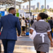 Black African cleaning and hospitality professionals approach a trade exhibition.