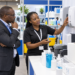 A Black African facility manager reviews washroom dispensers at a trade-show booth.