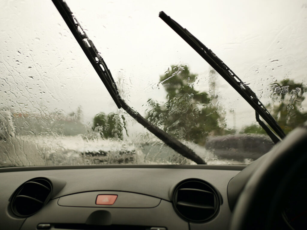 Rain-soaked windshield with wipers in motion.