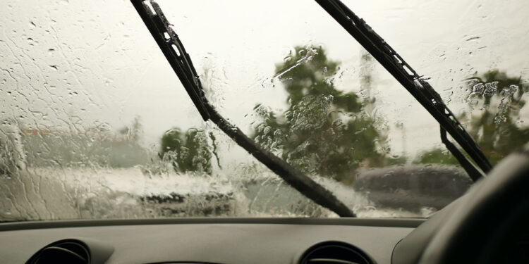Rain-soaked windshield with wipers in motion.