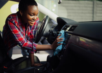 Person cleaning car dashboard with a cloth.