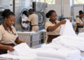 A hotel laundry team sorts fresh linens beside commercial washers.