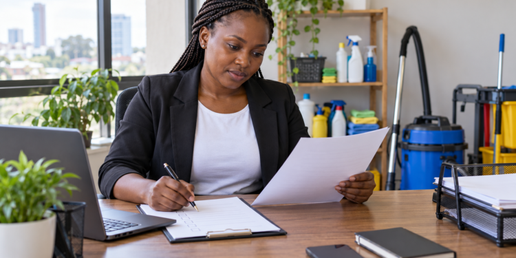 A Black African entrepreneur reviews business registration paperwork at a Nairobi office desk.