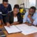 A Black African business owner organizes tender documents at a work desk.
